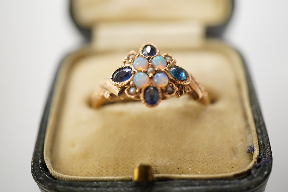 A late Victorian yellow metal, sapphire, opal and seed pearl cluster set dress ring, (one stone a paste replacement), size N, gross weight 2.2 grams.